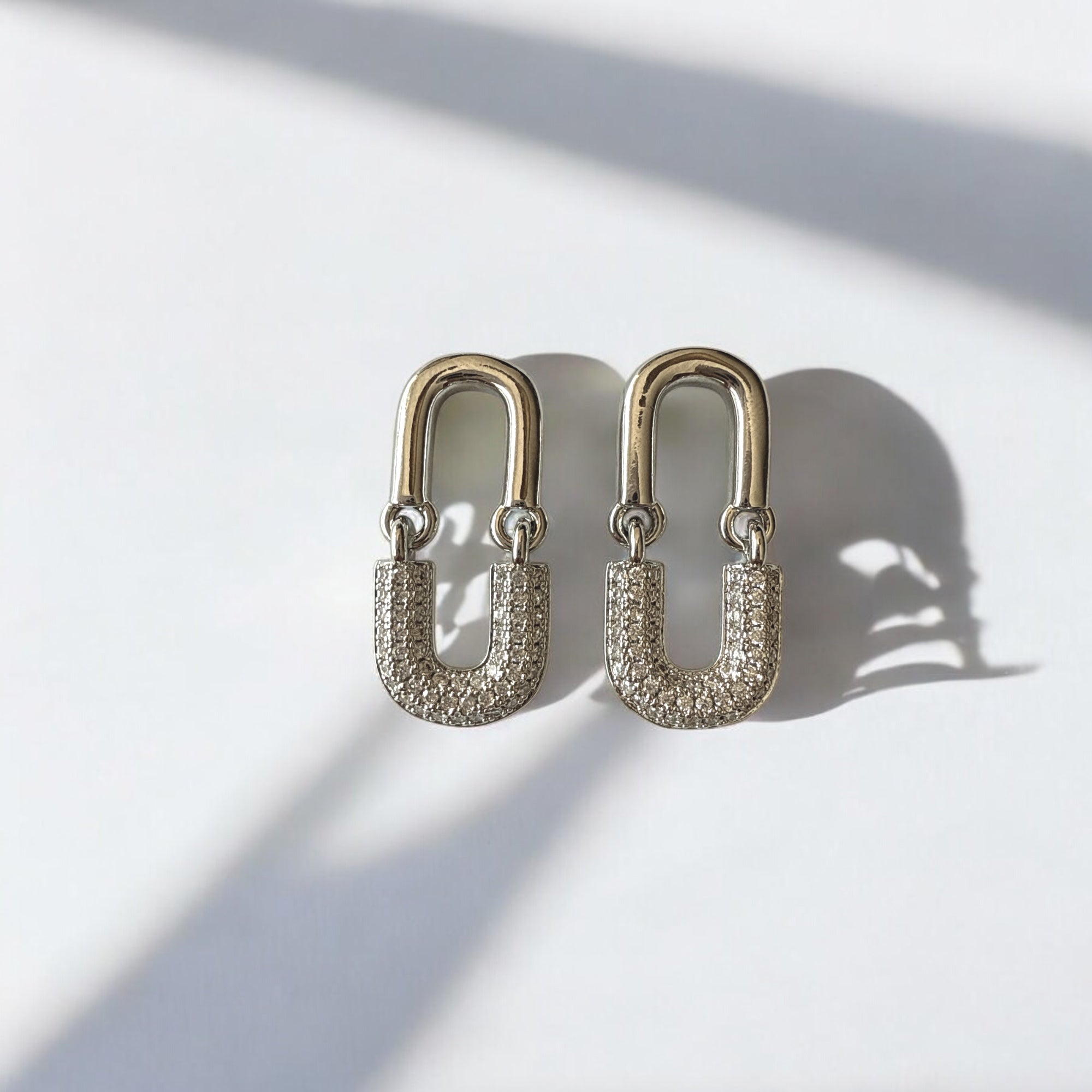 Aretes en forma de clip de acero plateado con circones blancos.