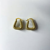 Aretes dorados con circones en diseño geométrico sobre fondo blanco.