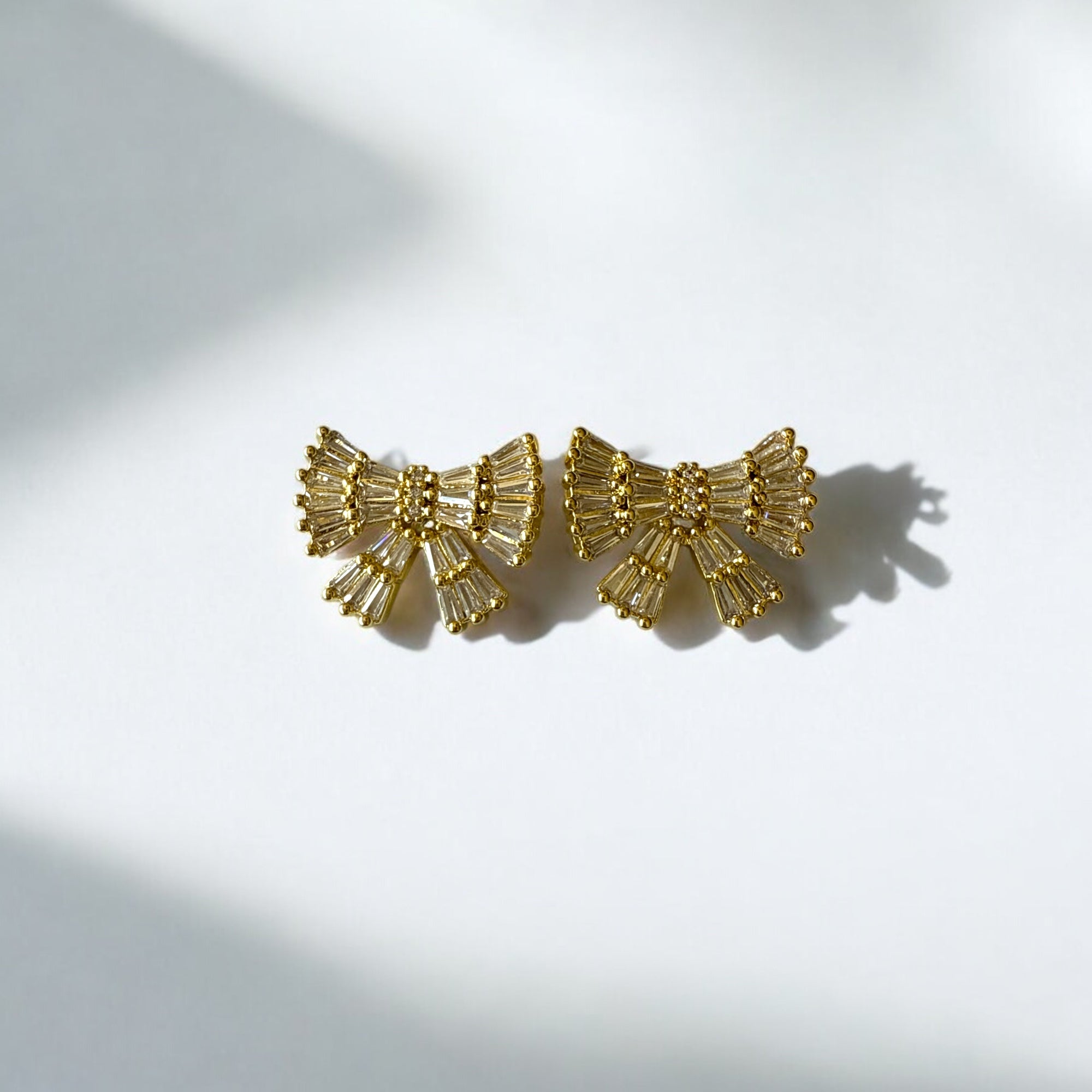 Aretes lazo dorado con circones blancos en acero bañado en oro, diseño femenino y sofisticado.