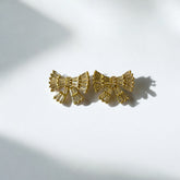 Aretes lazo dorado con circones blancos en acero bañado en oro, diseño femenino y sofisticado.