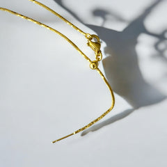 Collar de acero bañado en oro con dije de caracola natural y cadena tipo serpiente de 46 cm, regulable y 1 mm de espesor. Diseño sofisticado y elegante.