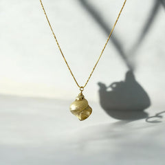Collar de acero bañado en oro con dije de caracola natural y cadena tipo serpiente de 46 cm, regulable y 1 mm de espesor. Diseño sofisticado y elegante.