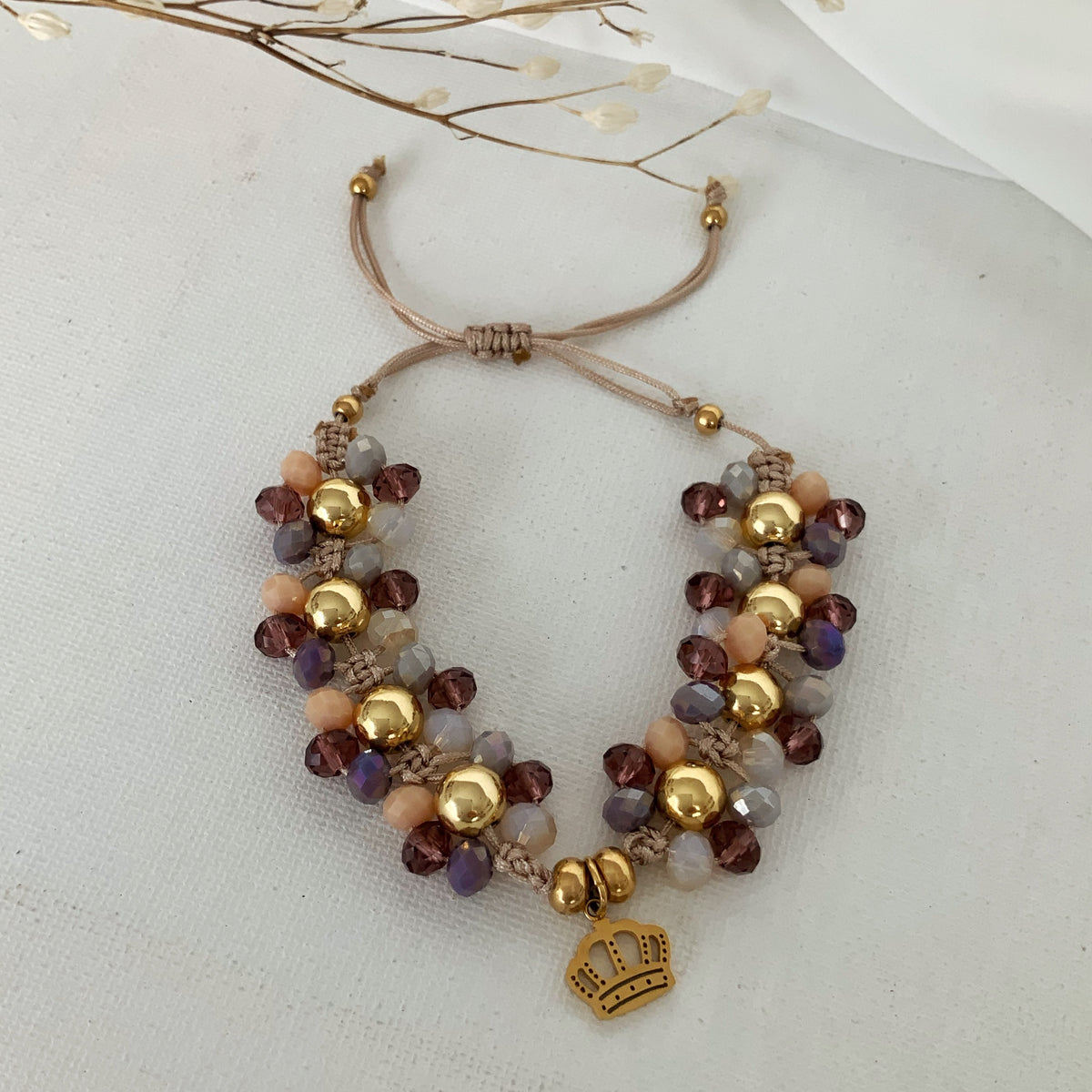 Pulsera de hilo ajustable con pedrería tejida y dije de corona