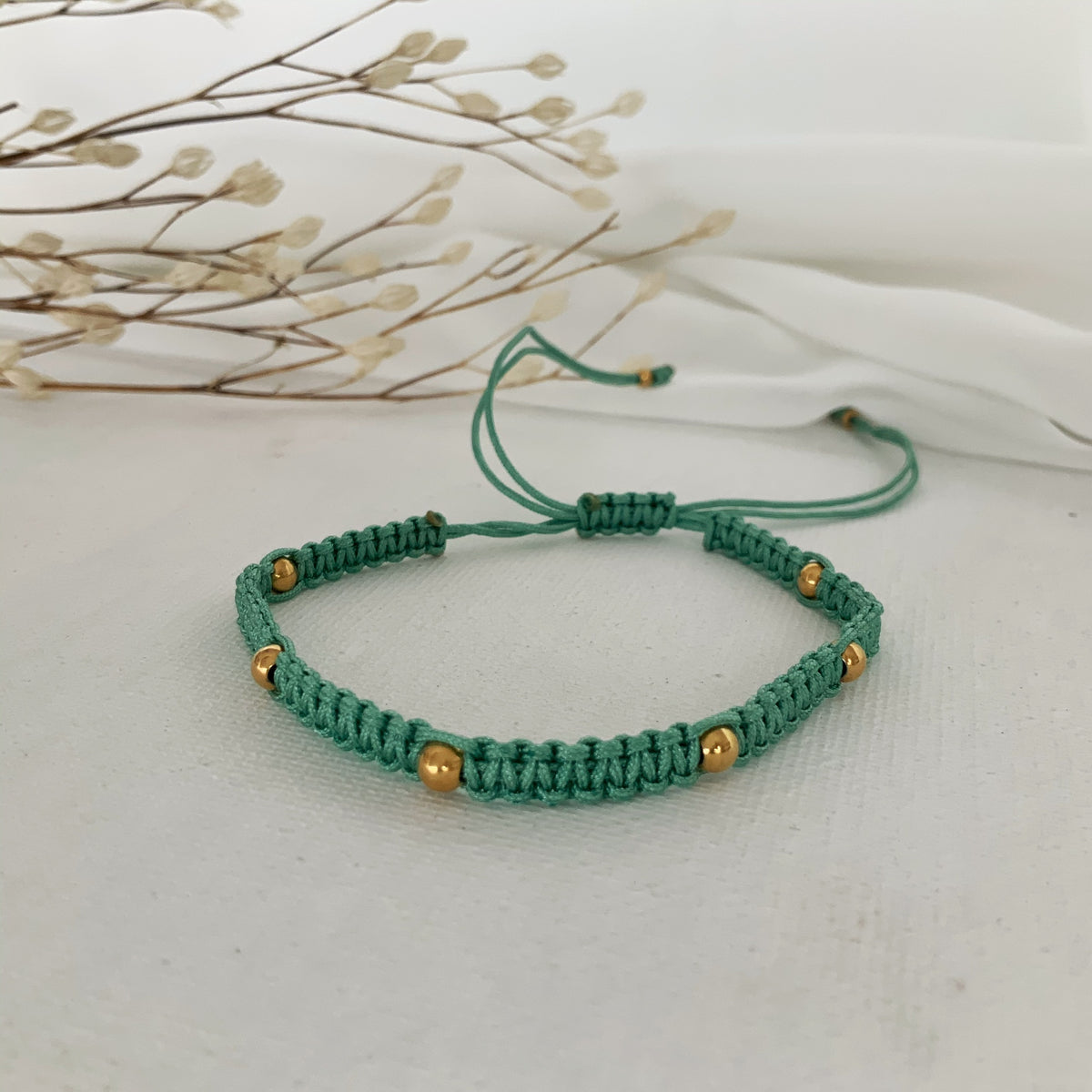 Pulsera de hilo ajustable verde agua y bolitas doradas