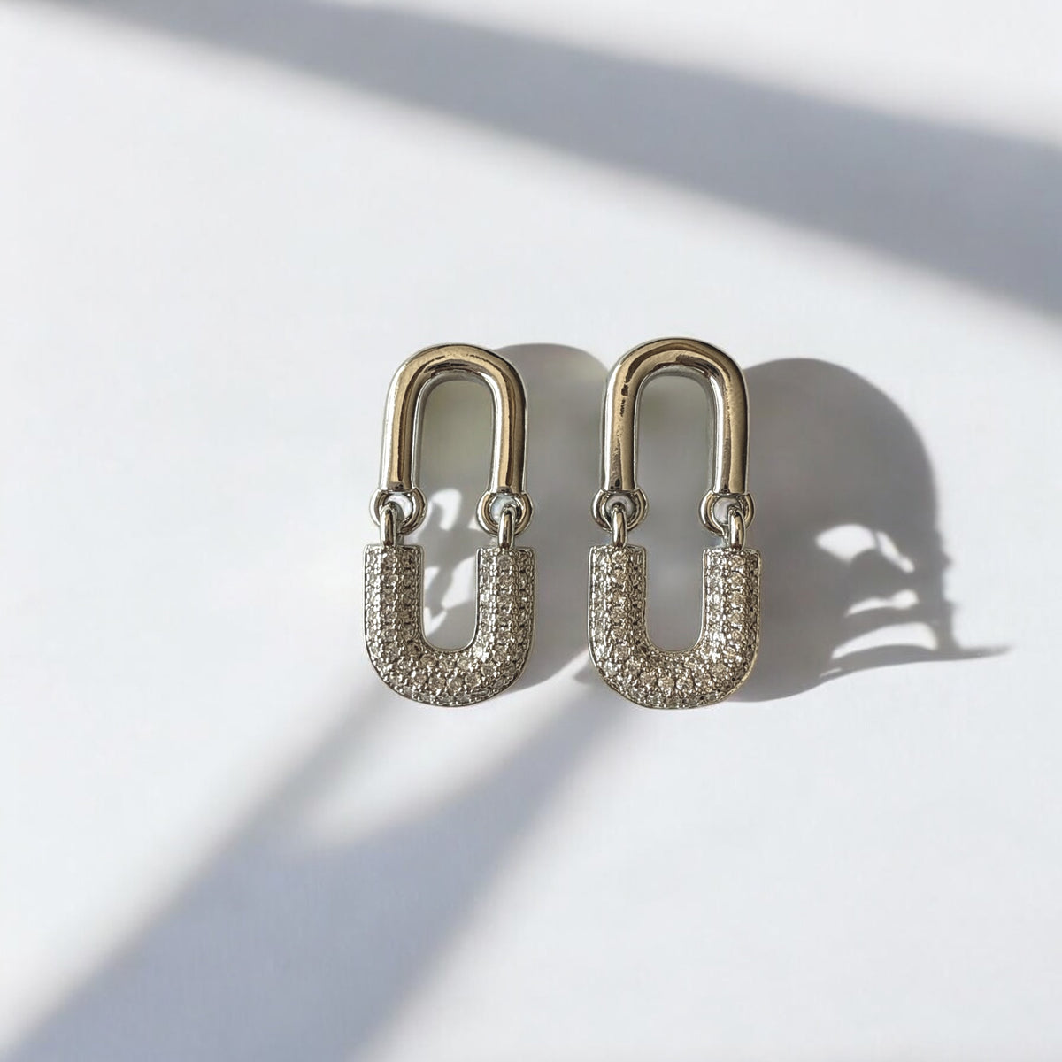 Aretes en forma de clip de acero plateado con circones blancos.