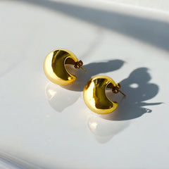 Aretes dorados de acero bañado en oro sobre fondo blanco