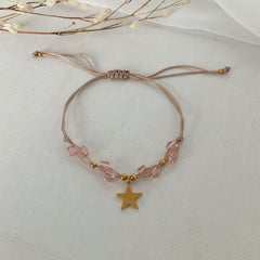 Pulsera de hilo con pedrería rosa y dije de estrella dorada