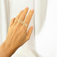 Anillo doble dorado con circones blancos sobre fondo neutro.