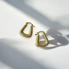 Aretes dorados con circones en diseño geométrico sobre fondo blanco.