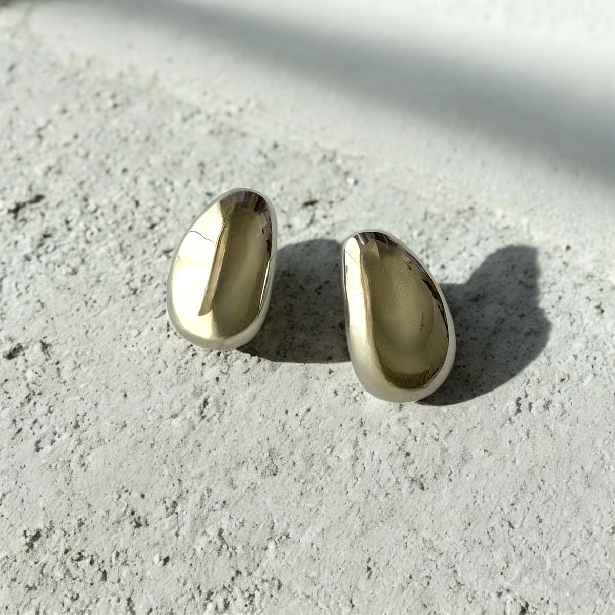 Aretes plateados de acero inoxidable con diseño minimalista y acabado pulido. Modernos y versátiles.