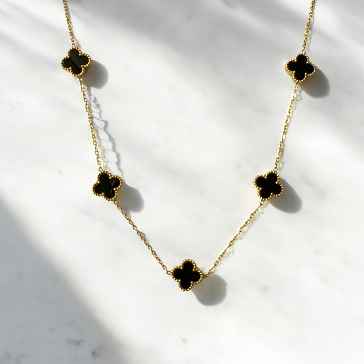 Collar de acero con tréboles negros esmaltados. Diseño elegante y sofisticado.