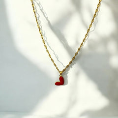 Collar de acero bañado en oro con dije de corazón rojo esmaltado y cadena espiga de 4 mm y 44 cm, regulable. Diseño romántico y elegante.