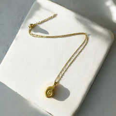 Collar de acero bañado en oro con dije de caracol texturizado y cadena fina de 1 mm y 45 cm, regulable. Diseño inspirado en la naturaleza.