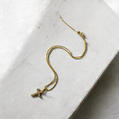 Collar de acero bañado en oro con dije de cruz con circones y cadena fina de 1 mm, regulable. Diseño elegante y sofisticado.