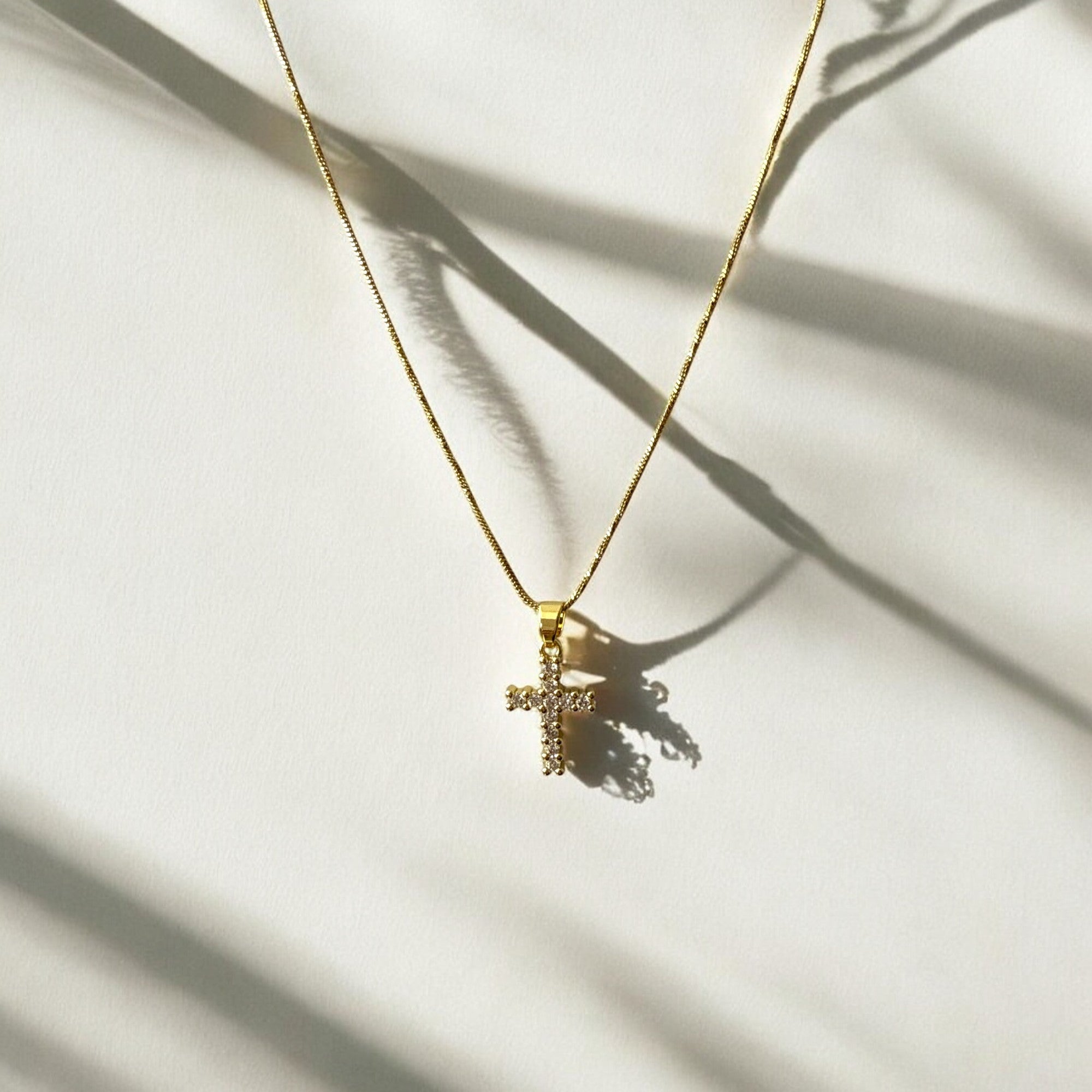 Collar de acero bañado en oro con dije de cruz con circones y cadena fina de 1 mm, regulable. Diseño elegante y sofisticado.