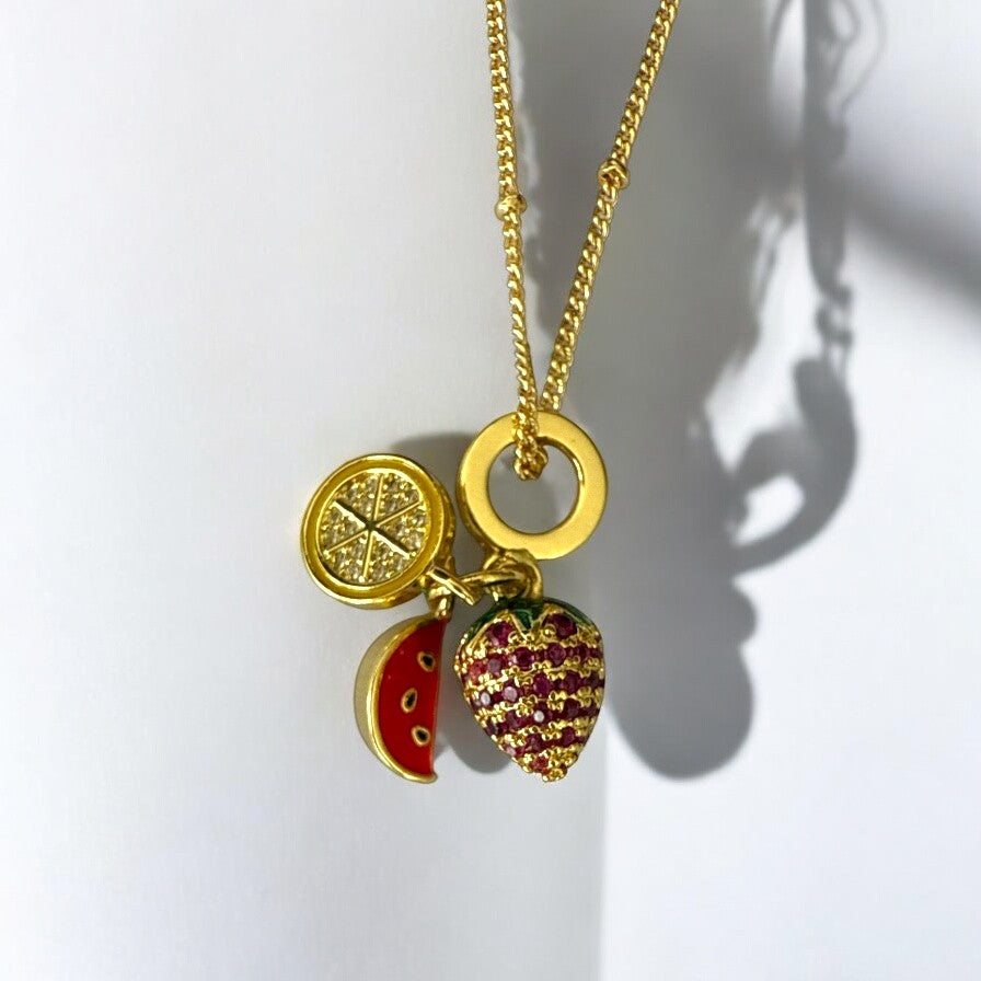 Detalle del collar de acero dorado con dije de fresa sandía y limón